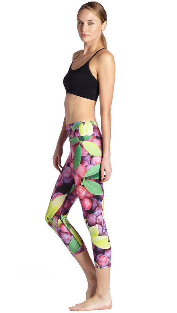 left side view of model wearing grapes and leaves themed printed capri leggings
