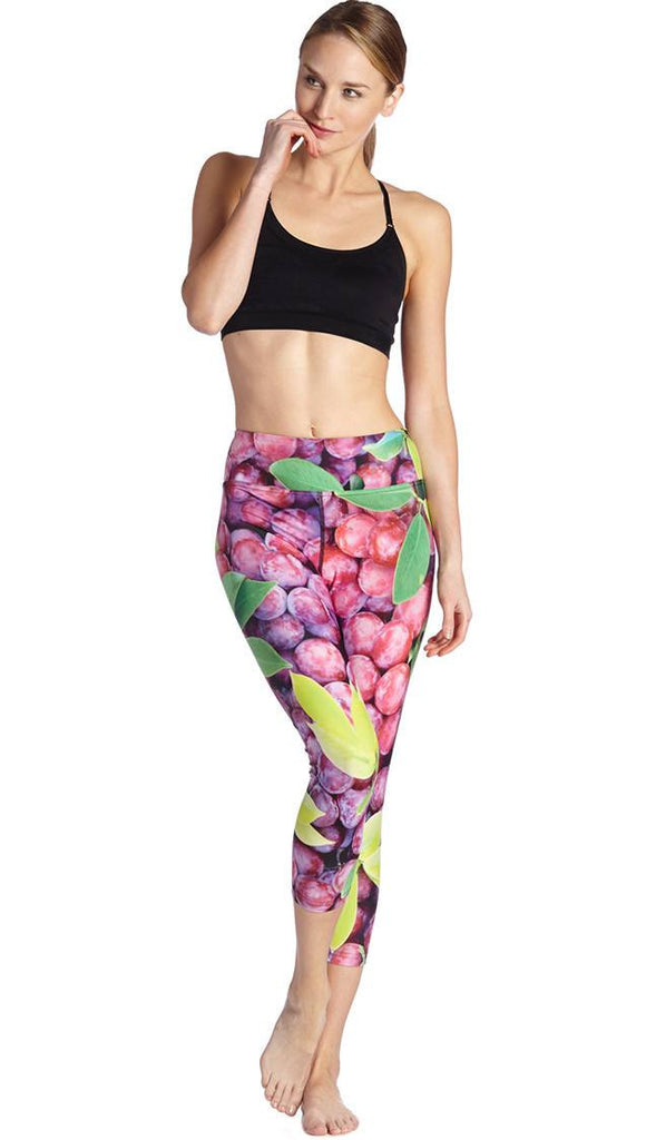 front view of model wearing grapes and leaves themed printed capri leggings
